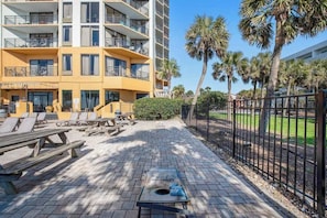 A courtyard with outdoor seating, a pool table, and a building with balconies. - The Patricia Grand 0528 (Myrtle Beach)