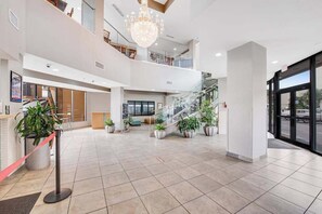 Eine geräumige Lobby mit Treppe, Topfpflanzen und einer Kristallleuchter.