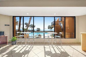 A room with a large window overlooking a pool and a building with a staircase. - The Patricia Grand 0528 (Myrtle Beach)