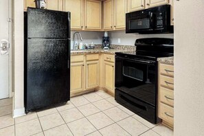 A kitchen with a refrigerator, microwave, stove, and cabinets. - The Patricia Grand 0304 (Myrtle Beach)
