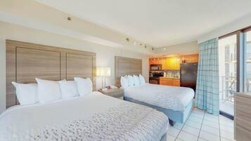 Quarto de hotel com duas camas, uma cozinha compacta e varanda com vista.