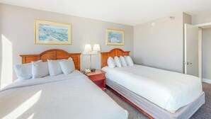 Ein Hotelzimmer mit zwei Einzelbetten, einem Nachttisch mit Lampe und zwei gerahmten Bildern an der Wand.