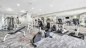 A modern gym with various cardio machines, free weights, and a mirrored wall. - The Patricia Grand 0624 (Myrtle Beach)