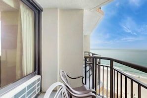 A balcony with a view of the ocean, a chair, and a window with curtains. - The Patricia Grand 1238 (Myrtle Beach)