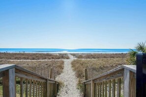Ein Holzweg führt zu einem Strand mit freiem Blick auf den Ozean.