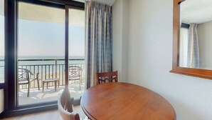 A room with a wooden table and chairs, a large window with a view of the beach, and a balcony with outdoor furniture. - The Patricia Grand 0628 (Myrtle Beach)