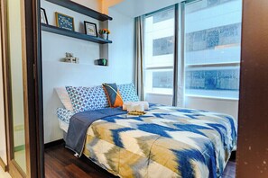 Un dormitorio con una cama, un ventanal y una estantería con objetos.