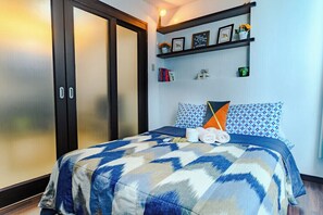 Una habitación de hotel con una cama, un armario y una estantería con objetos decorativos.