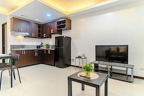 A modern kitchen with dark wood cabinets, a black refrigerator, and a built-in TV. - Comfortable City Escape (Taguig City)