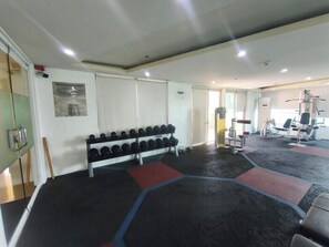 A gym with exercise equipment, a rack of dumbbells, and a mirror. - Comfortable City Escape (Taguig City)