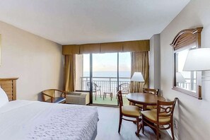 A hotel room with a bed, a dining table, chairs, a balcony with a view, and a window with curtains. - The Patricia Grand 0728 (Myrtle Beach)