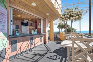 Eine Außenbar mit Theke, Sitzgelegenheiten und Blick auf den Ozean.