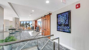 Um interior moderno com escada, área de refeições e um letreiro para o Indigo Coastal Kitchen.