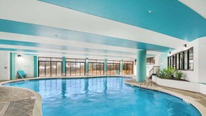 Ein überdachter Pool mit Glaswänden, gefliestem Boden und blauer Decke.