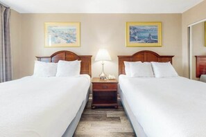 A hotel room with two beds, a nightstand with a lamp, and two framed pictures on the wall. - The Patricia Grand 1002 (Myrtle Beach)