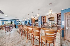 A bar area with wooden chairs, a bar counter, and hanging pendant lights. - The Patricia Grand 0928 (Myrtle Beach)