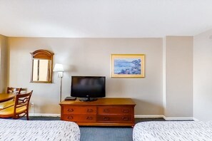 A hotel room with a bed, a desk with a chair, a television, a dresser, a lamp, and a framed picture on the wall. - The Patricia Grand 0928 (Myrtle Beach)