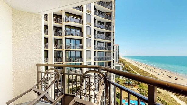 Un hotel di grandi dimensioni con numerosi balconi affacciati su una spiaggia.