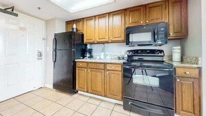 Una cocina con armarios de madera, un refrigerador negro, un microondas y una estufa.