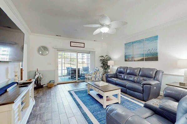 A living room with a sofa, coffee table, and a ceiling fan. - Magnolia Pointe Unit 103 (Myrtle Beach)