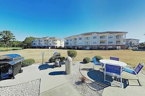 A hotel with outdoor seating, a barbecue grill, and a trash can. - Magnolia Pointe Unit 103 (Myrtle Beach)
