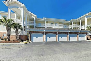 A multi-story building with a covered parking area and multiple garage doors. - Magnolia Pointe Unit 103 (Myrtle Beach)