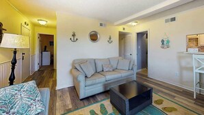 Ein Wohnzimmer mit Sofa, Couchtisch, Lampe und einem gemusterten Teppich.