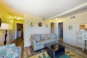 A living room with a sofa, a coffee table, a lamp, and a patterned rug. - Waipani Unit C-15 Condo (North Myrtle Beach)