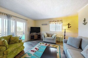 A living room with a sofa, a television, a small table, and a decorative rug. - Waipani Unit C-15 Condo (North Myrtle Beach)