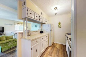 A compact kitchen with white cabinetry, a refrigerator, a microwave, and a sink. - Waipani Unit C-15 Condo (North Myrtle Beach)