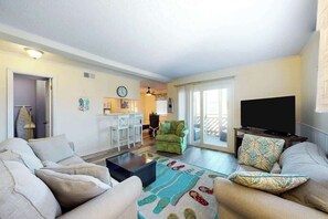 A living room with a sofa, a coffee table, a television, and a patterned rug. - Waipani Unit C-15 Condo (North Myrtle Beach)