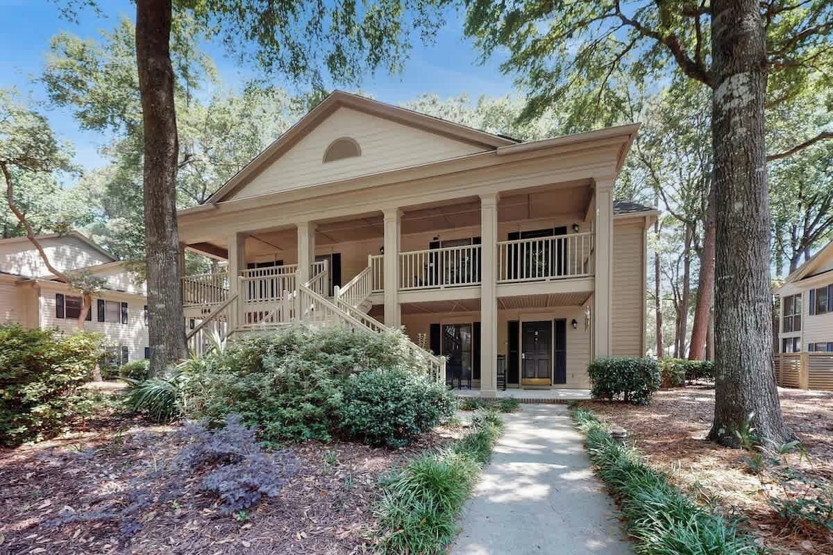 A two-story building with a covered porch and a staircase leading to the upper level.