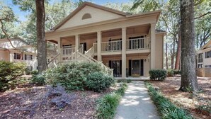 A two-story building with a covered porch and a staircase leading to the upper level. - Pawleys Island Unit #2 (Pawleys Island)