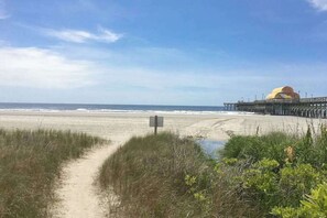 A beach with a pier and a building with a dome-like structure. - Dunes Pointe Unit C-14 (Myrtle Beach)