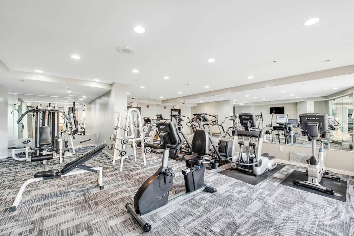 Et fitnesscenter med forskellig træningsudstyr, herunder løbebånd, spinningcykler og styrkemaskiner.