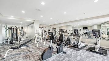 Et fitnesscenter med forskellig træningsudstyr, herunder løbebånd, spinningcykler og styrkemaskiner.