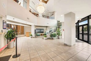 A spacious lobby with a staircase, potted plants, and a chandelier. - The Patricia Grand 1408 (Myrtle Beach)