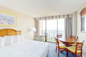 A hotel room with a bed, a dining table with chairs, a balcony with a view, and a painting on the wall. - The Patricia Grand 1428 (Myrtle Beach)