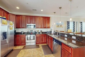 A modern kitchen with wooden cabinets, stainless steel appliances, and a granite countertop. - Corals and Oars Retreat (Myrtle Beach)