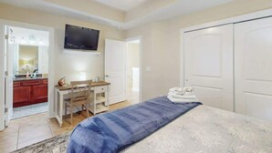 A bedroom with a bed, a desk, a chair, a television, and a wardrobe. - Corals and Oars Retreat (Myrtle Beach)