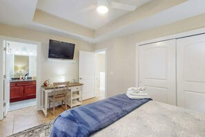 A bedroom with a bed, a desk, a chair, a television, and a wardrobe. - Corals and Oars Retreat (Myrtle Beach)