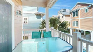 A glass-top table on a balcony with a white railing and a view of neighboring houses. - Corals and Oars Retreat (Myrtle Beach)