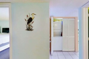A hallway with a wall-mounted bird decoration, a white door, and a tiled floor. - Bay Watch Resort 0811 (North Myrtle Beach)