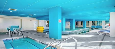 A swimming pool area with multiple lanes, a changing room, and a seating area with tables and chairs.