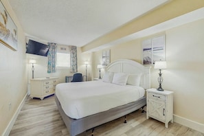 A bedroom with a bed, bedside tables, a desk, and a TV. - Bay Watch Resort 1438 (North Myrtle Beach)