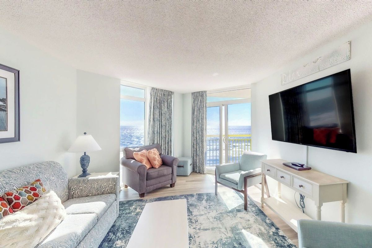 A modern living room with a large TV, comfortable seating, and a view of the city.