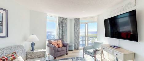 A modern living room with a large TV, comfortable seating, and a view of the city.