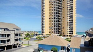 Ein Hochhaus-Hotel mit mehreren Balkonen, einem Parkplatz und Blick auf den Strand.