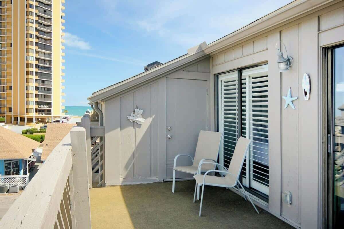 A balcony with two white chairs, a starfish decoration, and a view of the ocean.