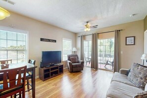 Ein Wohnzimmer mit Fernseher, Sofa und Essbereich.